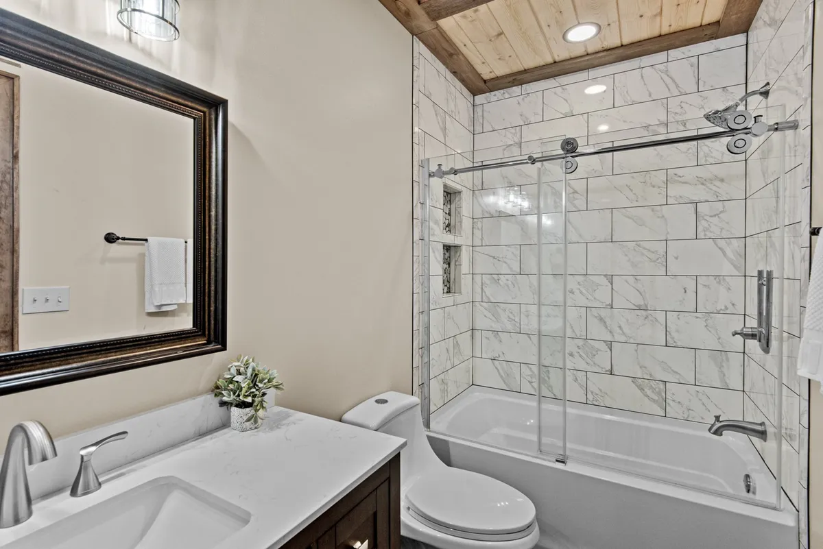 A bright, modern bathroom with a large mirror, chic vanity with sink, and a walk-in shower. The space is clean and contemporary, with subtle decor touches that amplify the spa-like feel.