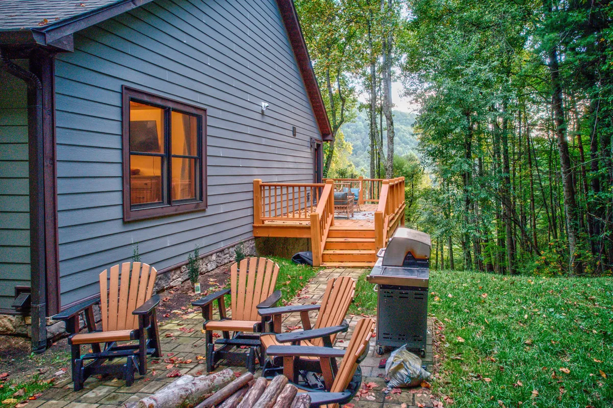 A spacious wooden deck with Adirondack chairs, a grill, and views of surrounding trees. The cozy setup invites guests to relax outdoors, dine al fresco, or share stories by the fire after a day of adventure.