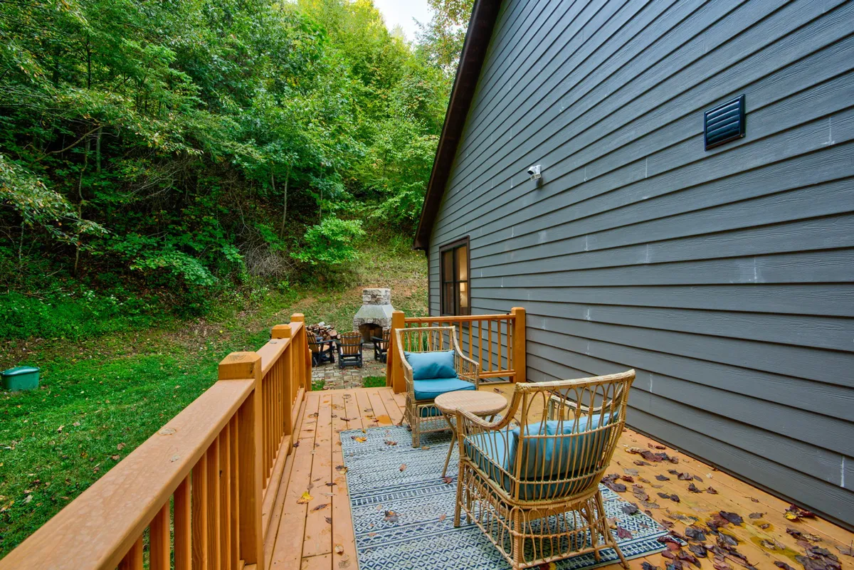 An inviting exterior shot of a deck with comfortable seating, an outdoor grill, and lush greenery all around. The ambiance is perfect for either a peaceful morning coffee or lively evening entertaining after a day in the mountains.
